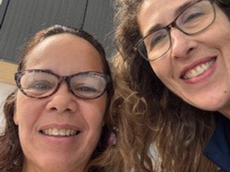 Two women with glasses smile into the camera.