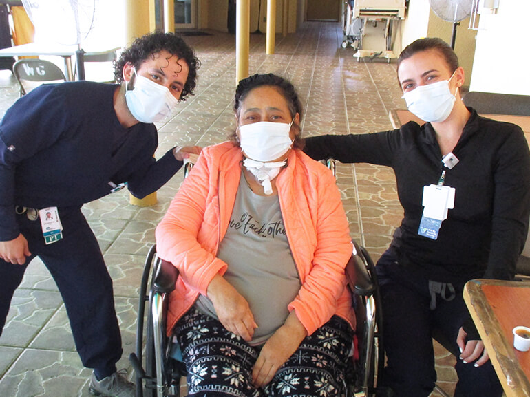 Jazmina Merced sitting in her wheelchair with her therapists.