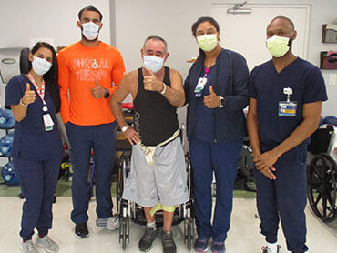 Lorenzo Estepe gives a thumbs up while surrounded by his therapy team.