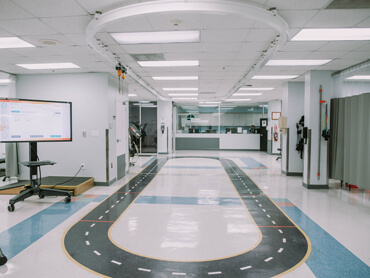 Therapy gym with small oval walking track and bright lighting.