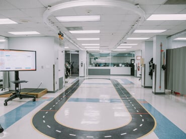 Therapy gym with small oval walking track and bright lighting.
