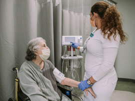 Nurse taking heart rate of older female patient.