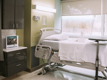 Patient room with hospital bed in front of a window.