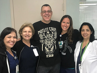 Jose smiling and standing in the middle of a group of female nurses and therapists.